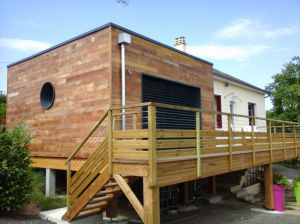 Belle extension ossature bois à SAINT CALAIS (72), avec plancher bois sur pilotis, avec terrasse, bardage red cedar, toit plat, grande baie vitrée avec BSO (Brise Soleil Orientable).