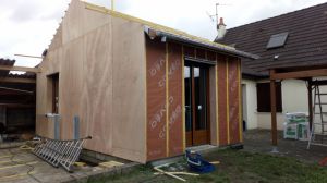 Création d'une extension ossature bois finition enduite sur St ouen (41), menuiserie coloris chêne doré et isolation performante, pose de volets roulants et porte de garage.